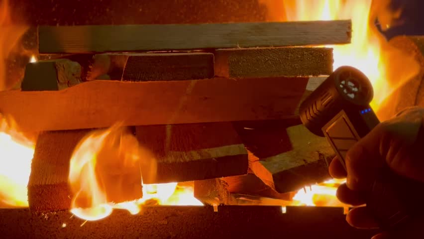 Close-up Man Builds Fire using an electric blower