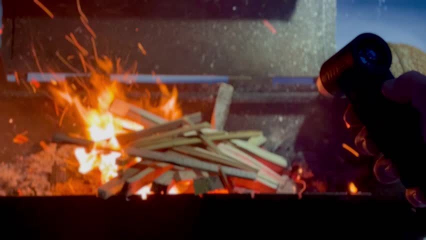 Close-up Man Builds Fire using an electric blower