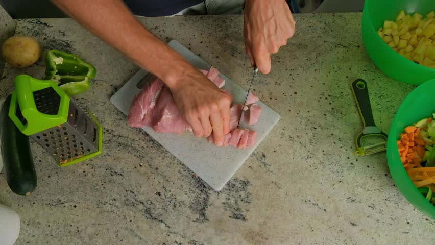 Close-up of a man cutting meat in the kitchen.