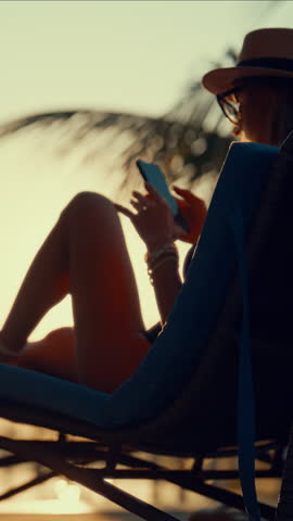 Unknown Female User With Smartphone Near Swimming Pool In Luxury Hotel, Vertical Video. Silhouette Of Woman Vacationer Surfing Internet By Mobile Phone Connecting To Free Wi-Fi Roaming In Traveling