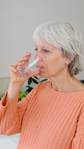 Happy senior adult woman holding a glass of water in the morning at home. Healthy life habit, lifestyle concept