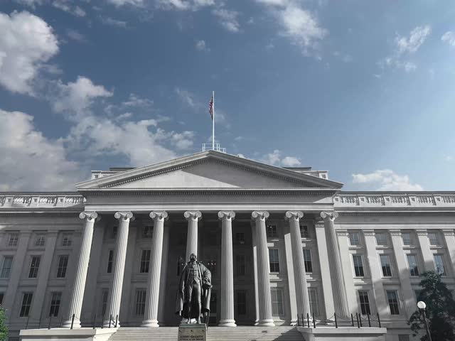 Department of the Treasury building and Albert Gallatin statue with clouds moving during day time in Washington DC.