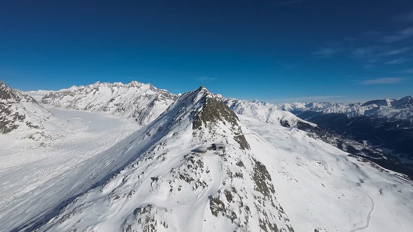 Drone aerial view over the peak of Aletsch Ski Resort in Switzerland at noon. Wonderful alpine landscape on a clear sunny day showcasing the Great Aletsch Glacier in background and top of the slope.