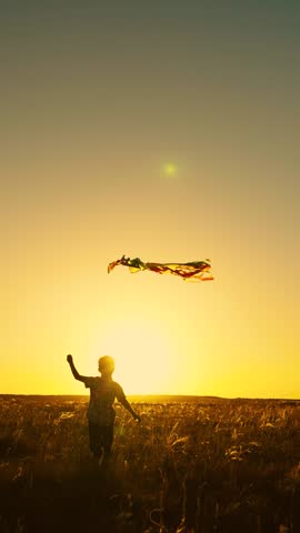 Flying kite in blue sky, silhouette of child. Happy boy playing with flying kite in nature in rays of summer sun. Boy plays kite with toy. Kid dream of fly, freedom travel. Child runs through meadow