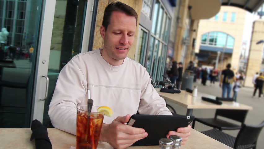 A man uses his tablet PC outside at a roadside cafe.