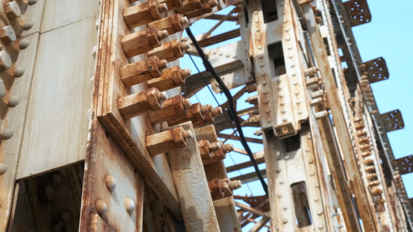 Thoughtful girl on rusty bridge. A view of pensive teen stand on the rusty bridge against blue sky.