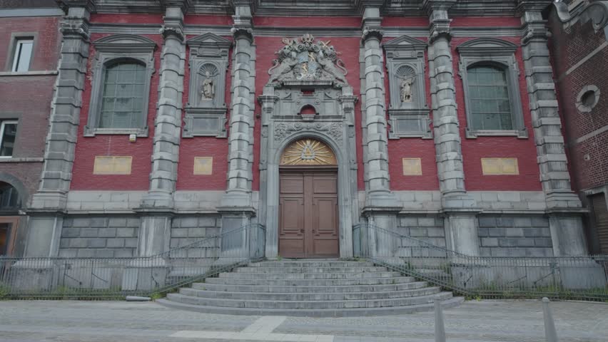 A red Baroque church facade with statues, dramatic architecture in Liège, Belgium