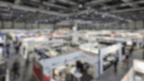 Blurred attendees explore booths in a busy exhibition hall - Powered by Shutterstock - Get 15% off with code: PIKWIZARD15