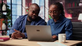 Black man and woman working in their cozy loft discussing digital marketing strategy on a laptop, pointing at online tools. Supporting each other in their remote freelancing journey. Camera B. - Powered by Shutterstock - Get 15% off with code: PIKWIZARD15