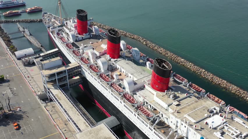 Top View of the Historic Queen Mary Cruise Ship Docked at Long Beach Harbor, Aerial Drone Footage in California, Maritime History and Coastal with Clear Blue Waters in Los Angeles Port