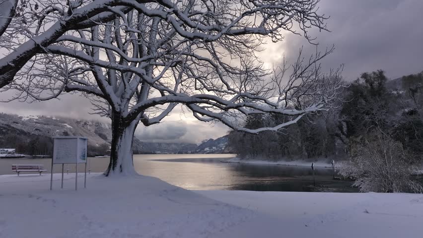 Aerial view of snow-covered Walensee lake in Amden, Switzerland – serene winter landscape with majestic mountains and reflective waters.