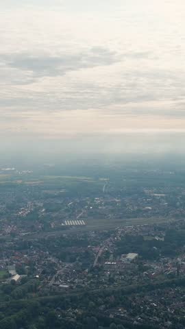 Vertical video. Ghent, Belgium. Sun rays and beautiful clouds. On the ground, a suburb of the city of Ghent with an industrial area and a railway, small houses. Ringvaart in Ghent - water channel, Ae