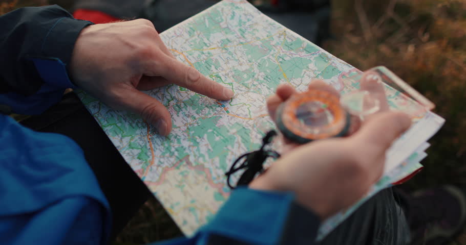 Close-up footage of a traveler's hands holding a map and compass in the ...
