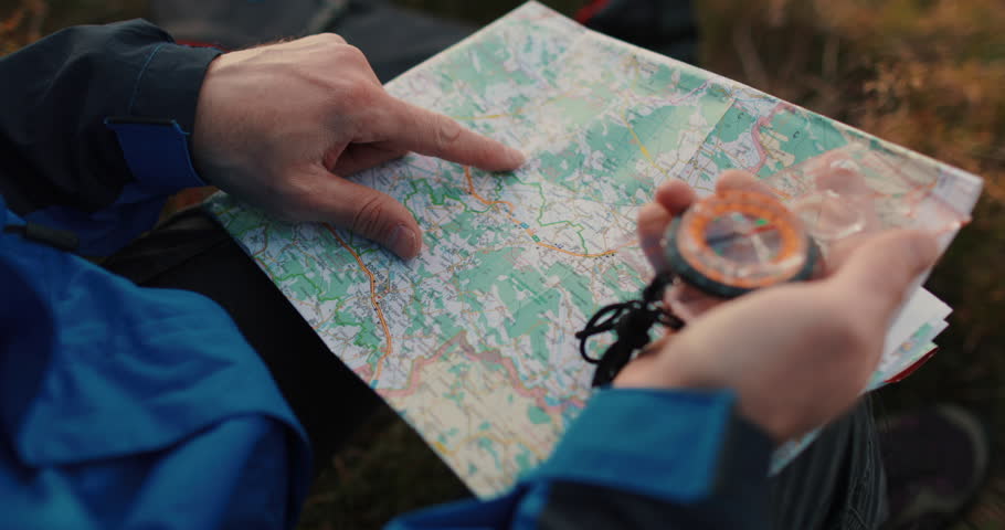 Close-up footage of a traveler's hands holding a map and compass in the ...