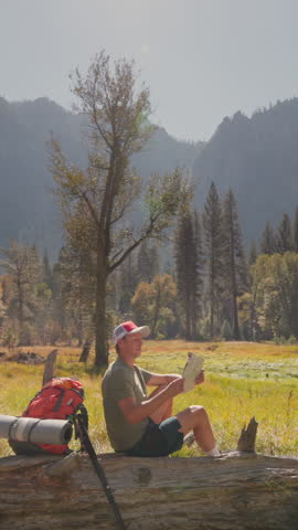 In the breathtaking and serene Yosemite National Park, a male hiker revels in the tranquility and beauty of nature, surrounded by majestic mountains and vibrant, lush trees all around him