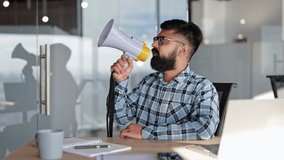 Bearded businessman in glasses speaks into megaphone in modern office. Male makes announcement to colleagues at business meeting. - Powered by Shutterstock - Get 15% off with code: PIKWIZARD15