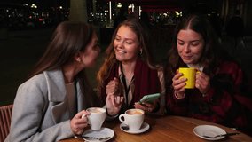 Three Young Women Are Sitting Together Sipping Their Coffee While Engaged In Conversation. One Woman Is Smiling While Checking a Smartphone. Their Joyful Presence Highlights Friendship And Connection - Powered by Shutterstock - Get 15% off with code: PIKWIZARD15