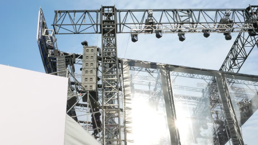 Installation or construction of a huge large stage for an outdoor concert. Metal structures for concert venues and installation of light and sound devices