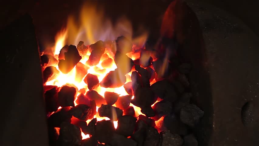 Blacksmith at work. Coal fire melts iron in a furnace for further processing with a hammer on an anvil in smithy, close-up. Traditional manual production in the forge, blacksmith workshop