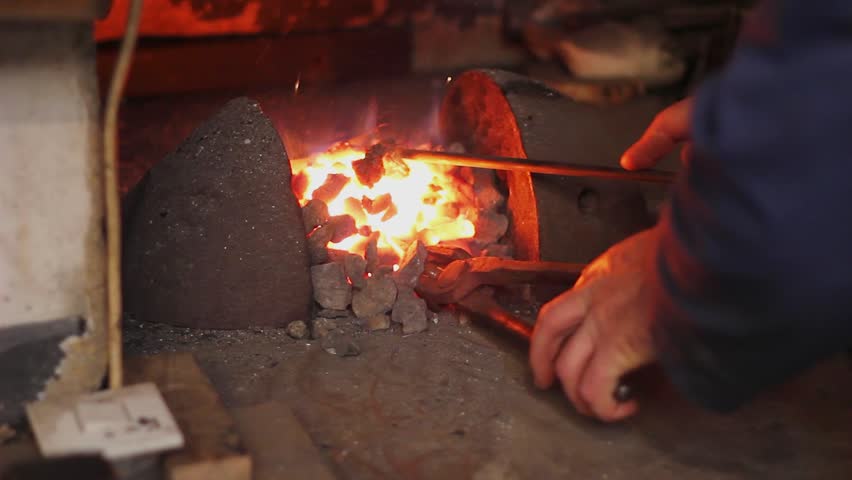Blacksmith at work. Coal fire melts iron in a furnace for further processing with a hammer on an anvil in smithy, close-up. Traditional manual production in the forge, blacksmith workshop - Powered by Shutterstock - Get 15% off with code: PIKWIZARD15