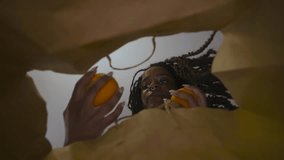 Young African American woman is taking apple from paper bag at home. - Powered by Shutterstock - Get 15% off with code: PIKWIZARD15