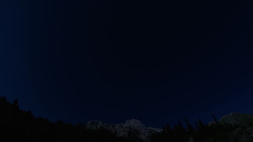Timelapse of the starry sky in the mountains under the moon, traces of stars