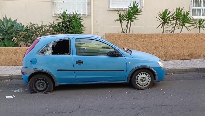 broken abandoned blue car with a broken window