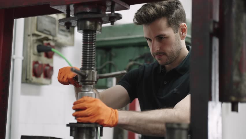 Technician operating industrial machinery in workshop