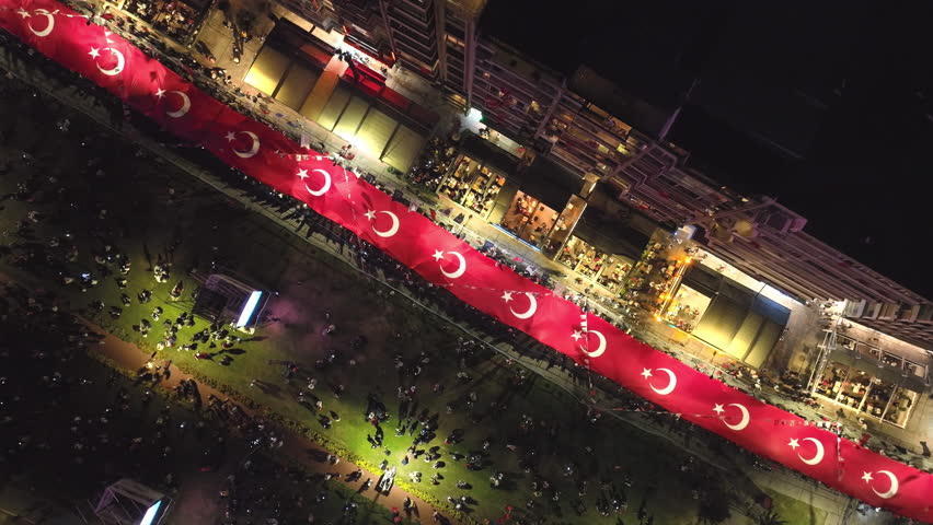 Republic Day is celebrated with great enthusiasm in Izmir. A giant Turkish flag waves in the darkness of the night as a crowd marches. A drone lands.