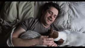 middle-aged man wakes up in bed with his dog, enjoying a cozy morning moment - Powered by Shutterstock - Get 15% off with code: PIKWIZARD15