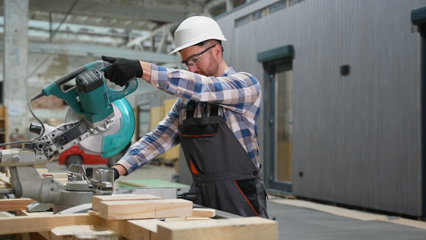 Carpenter cutting wood at modular home manufacturing site