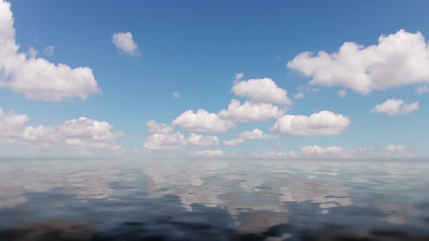 Blue sky. The clouds are running quickly. Clouds are reflected in the calm ocean