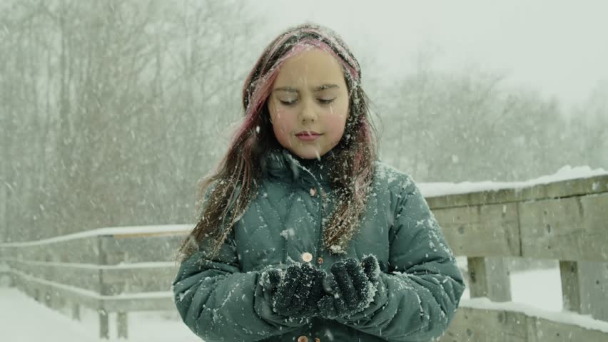 A Nine-Year-Old Girl In Winter Clothes Feels Snowfall On Her Hand By A Frozen Lake. She Looks Up At The Sky, Capturing The Quiet Beauty Of The Snowy Scene And The Stillness Of Winter.