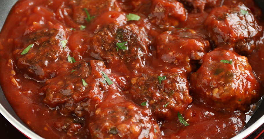 Cooking delicious meatballs with tomato sauce and herbs in pan, closeup