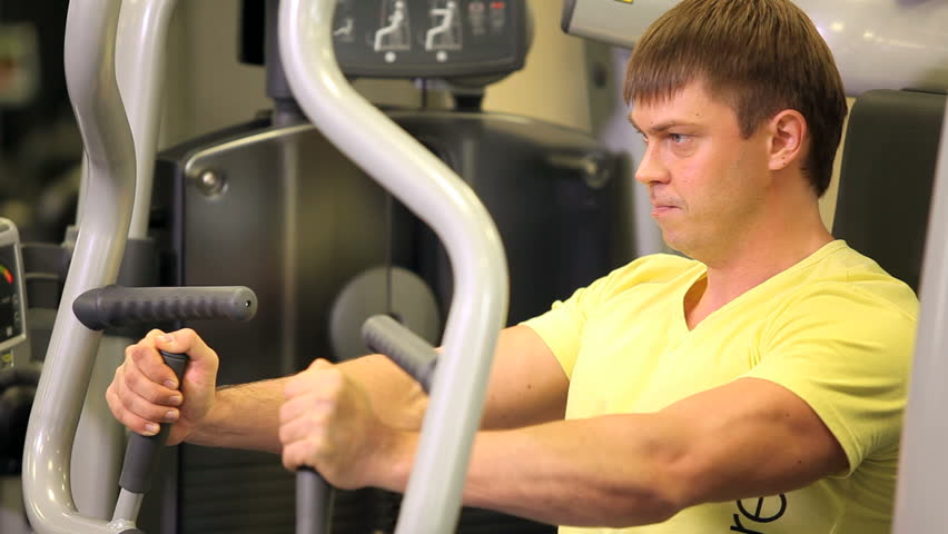 Athletic man exercising on sport machine in fitness center