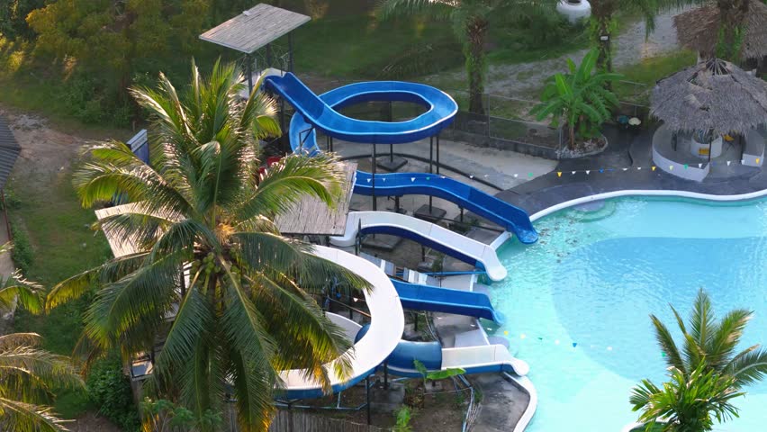 Slow establishing shot of multiple waterslides at a private pool in Thailand