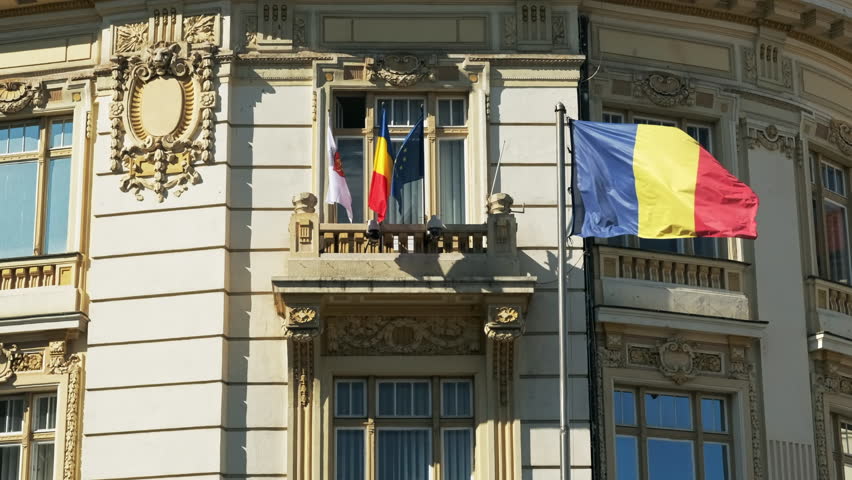 Facade of an old building with national and other flags in a town, Romania