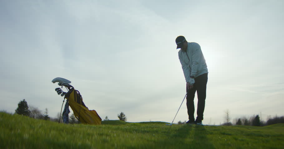 Male Golfer Hitting a Golf Ball in Slowmotion on Fairway - Sunny day