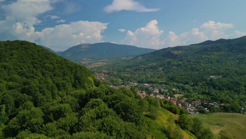 Picturesque rural landscape with houses gathered at the foot of the mountain in summer in Romania seen from above 4k