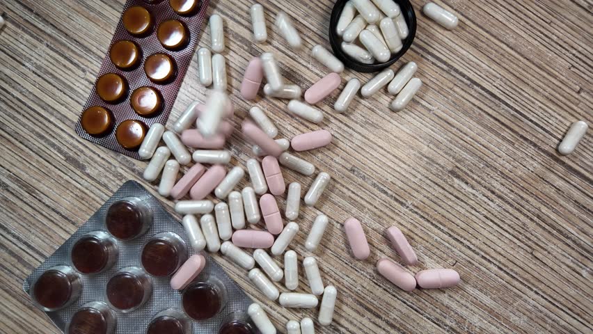 Different pills slowmotion. Colored pills of different shapes fall down. Falling drugs on a transparent background. Pharmaceutical business concept. Medicine capsules backdrop. Pharmacology concept.