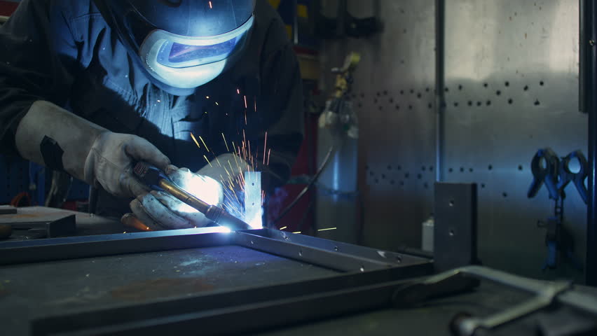 Skilled craftsman with a protective helmet and safety gear, carefully welding together metal pieces to create a sturdy construction, close up shot.