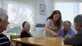 Geriatric nurse assisting elderly women playing dominoes in a retirement home, providing care and engagement - Powered by Shutterstock - Get 15% off with code: PIKWIZARD15