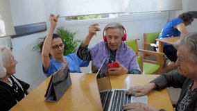 Elderly residents and a caregiver share a joyful moment, listening and dancing to music in a nursing home setting, using modern technology to connect - Powered by Shutterstock - Get 15% off with code: PIKWIZARD15