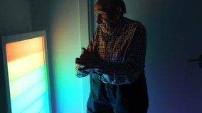 Senior man interacting with a colorful light panel, exploring sensory stimulation in a comforting geriatric environment - Powered by Shutterstock - Get 15% off with code: PIKWIZARD15
