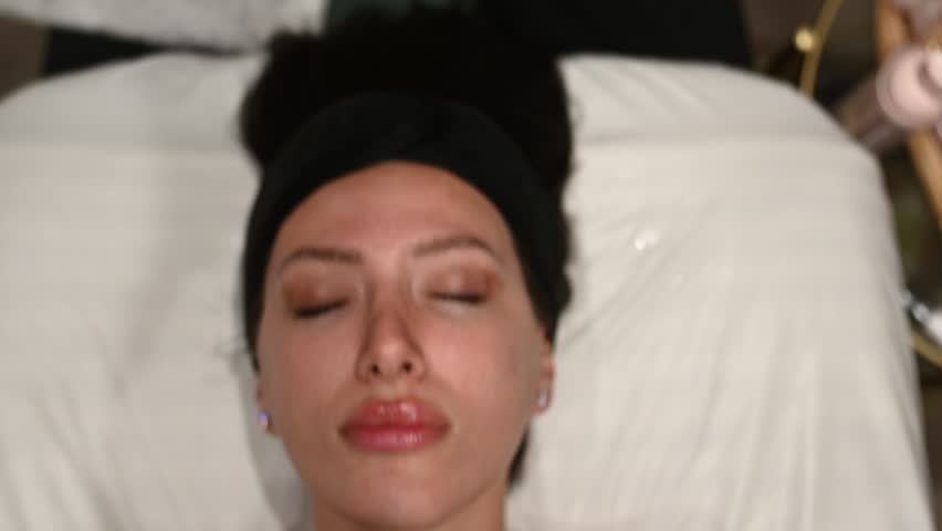 Woman receiving a relaxing facial massage with quartz stone.