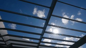 View of sky through structure made of metal beams. Beams form grid pattern and sun shining brightly through gaps creating starburst effect - Powered by Shutterstock - Get 15% off with code: PIKWIZARD15