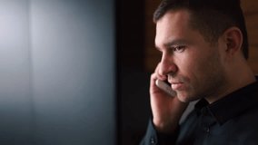 Side view video of young businessman in black shirt talking on phone and smile. Look at window and has conversation. Then guy walks to left. - Powered by Shutterstock - Get 15% off with code: PIKWIZARD15