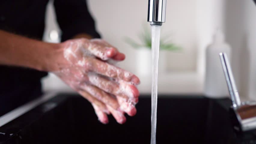 Side view and close up of man washing hands with soap above sink. Cleaning fingers and palms. Water pouring out of tap into sink in kitchen. Hand care and protection. - Powered by Shutterstock - Get 15% off with code: PIKWIZARD15