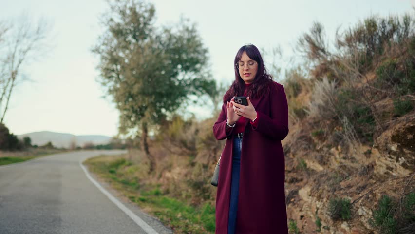 Young woman hailing a ride on a country road