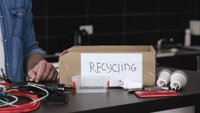 Young couple in kitchen during qurantine. Close up of recycling box for electric cables and cords. Man and woamn out also light bulbs into it. - Powered by Shutterstock - Get 15% off with code: PIKWIZARD15